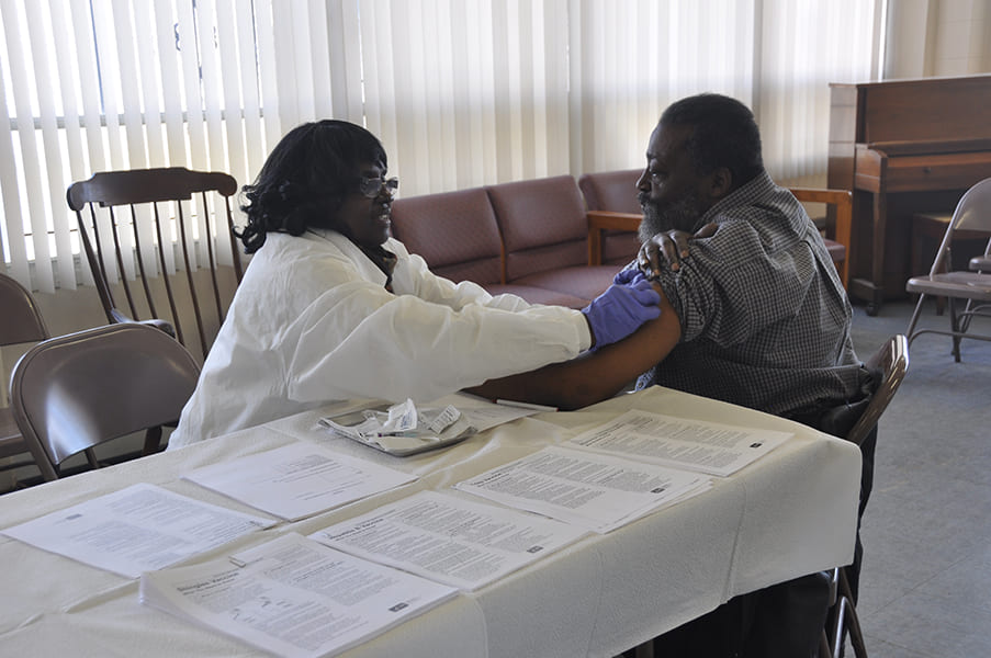 Clinician administering vaccination on Rose Centers participant's arm