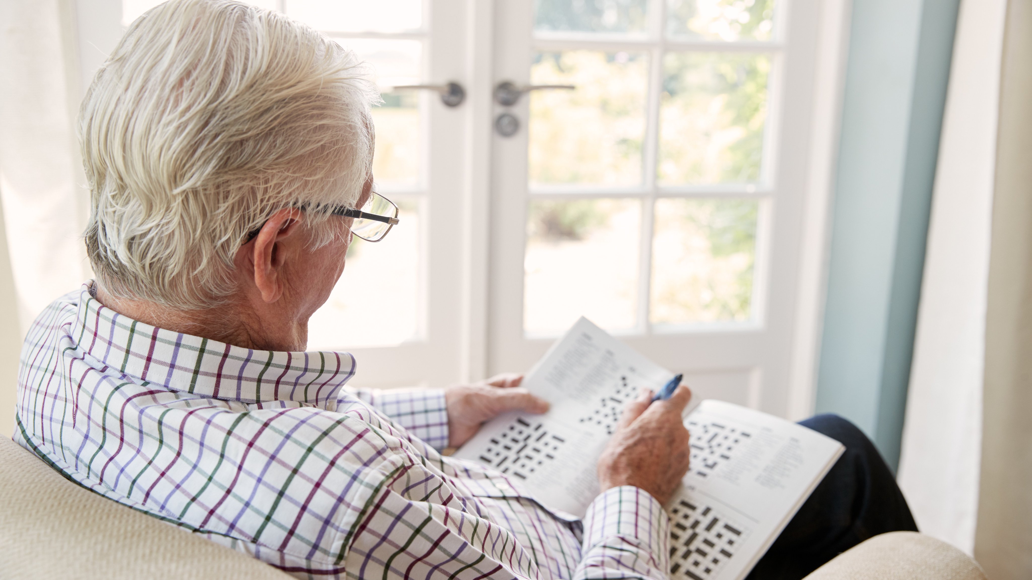 An older adult working on a crossword puzzle