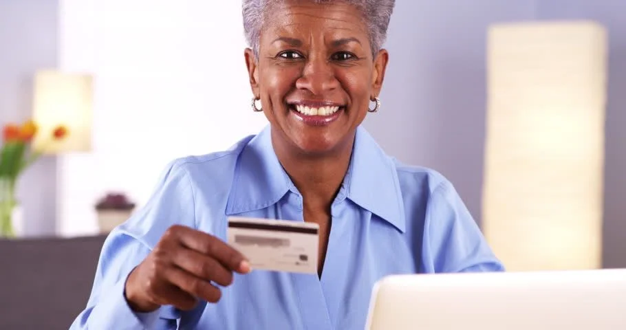 An older adult holding up her credit card