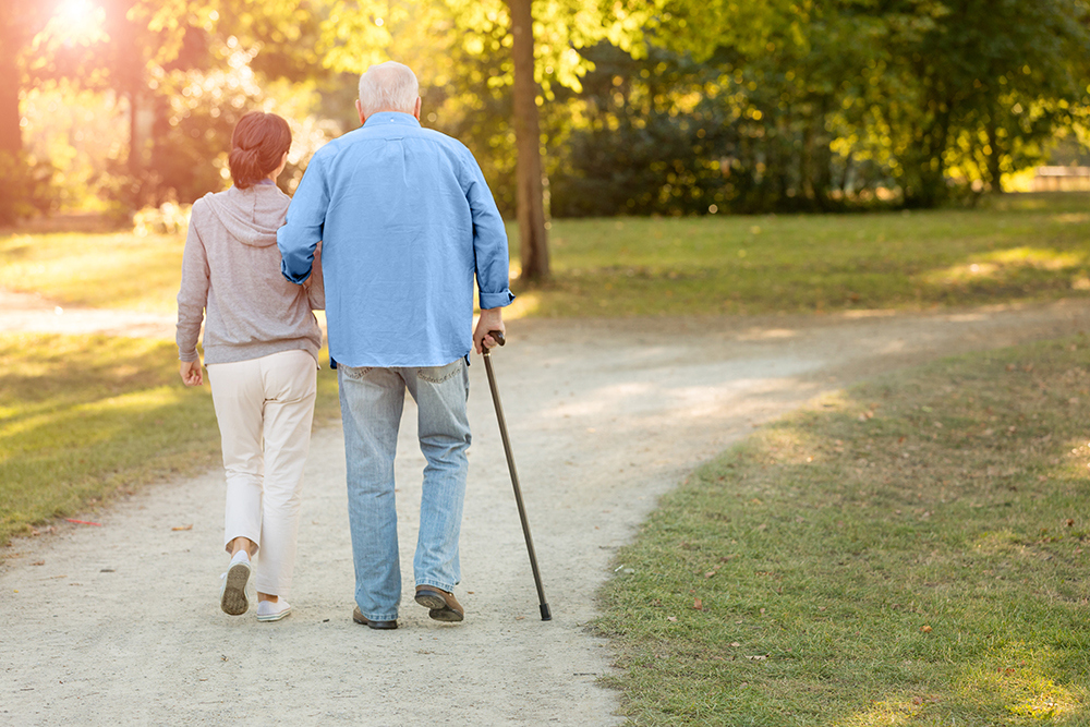 An older adult walking together with their caregiver