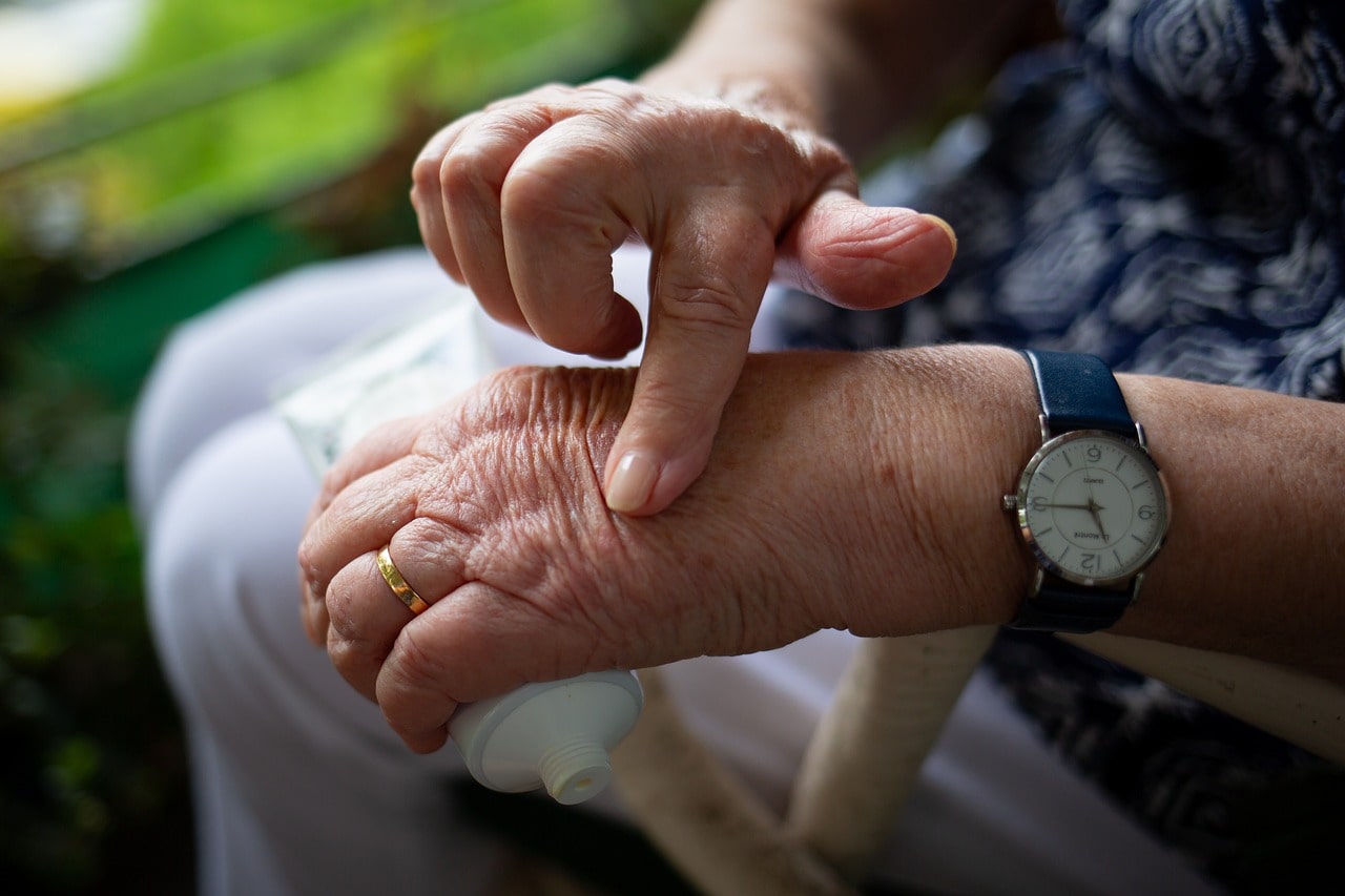 An older adult putting arthritis cream on their hands