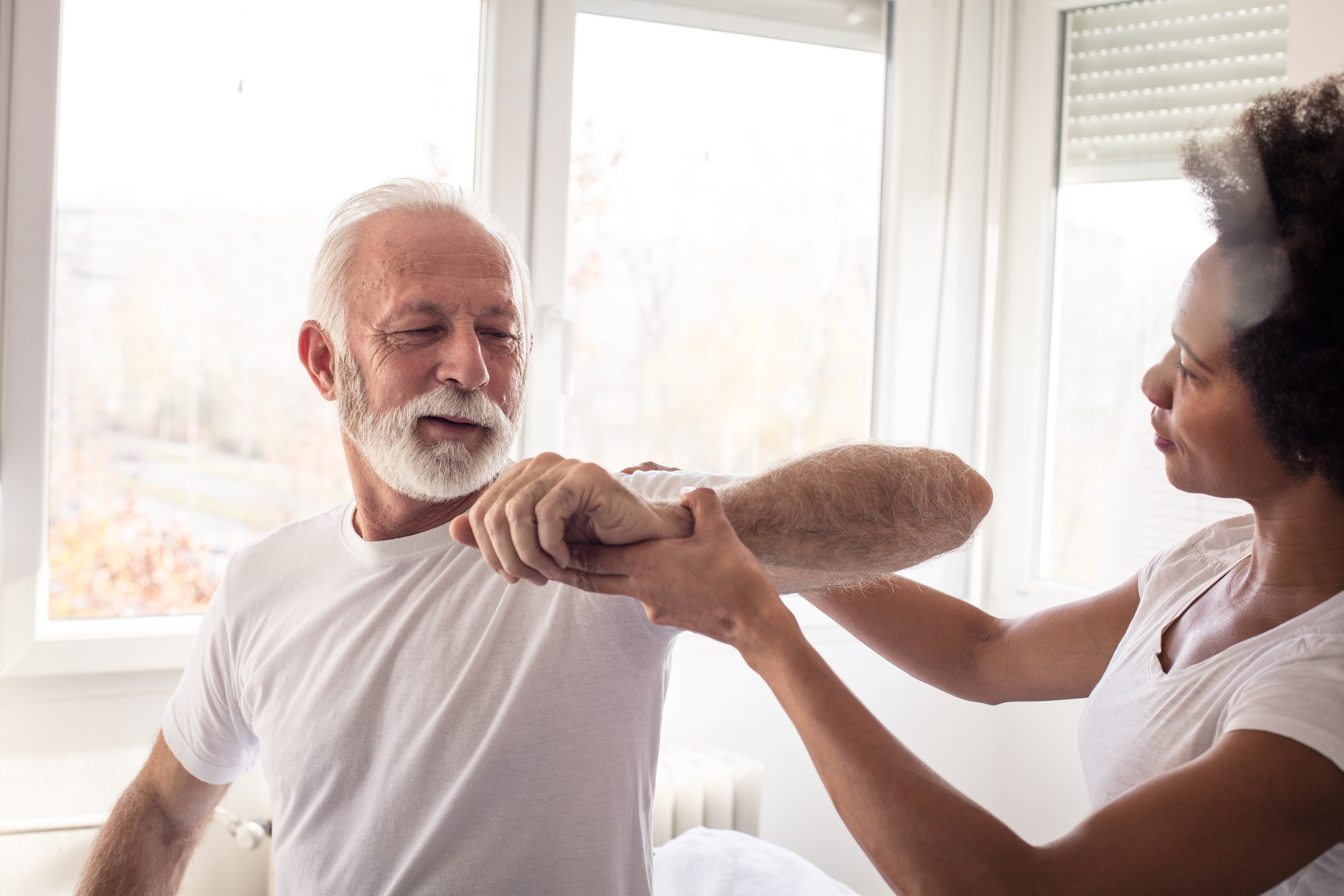 An older man undergoing physical therapy following a stroke