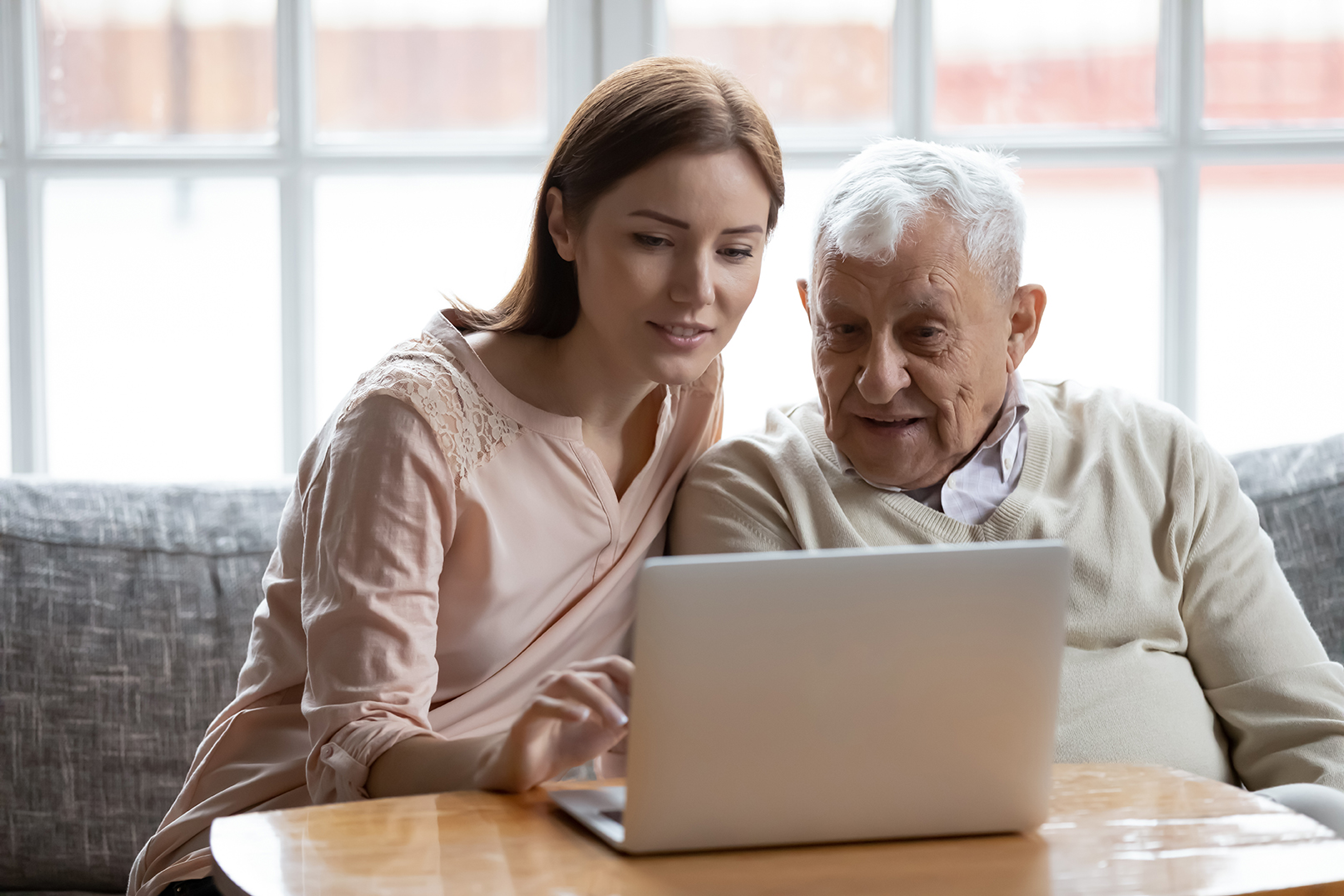 A caregiver and older loved one viewing different plans on a laptop