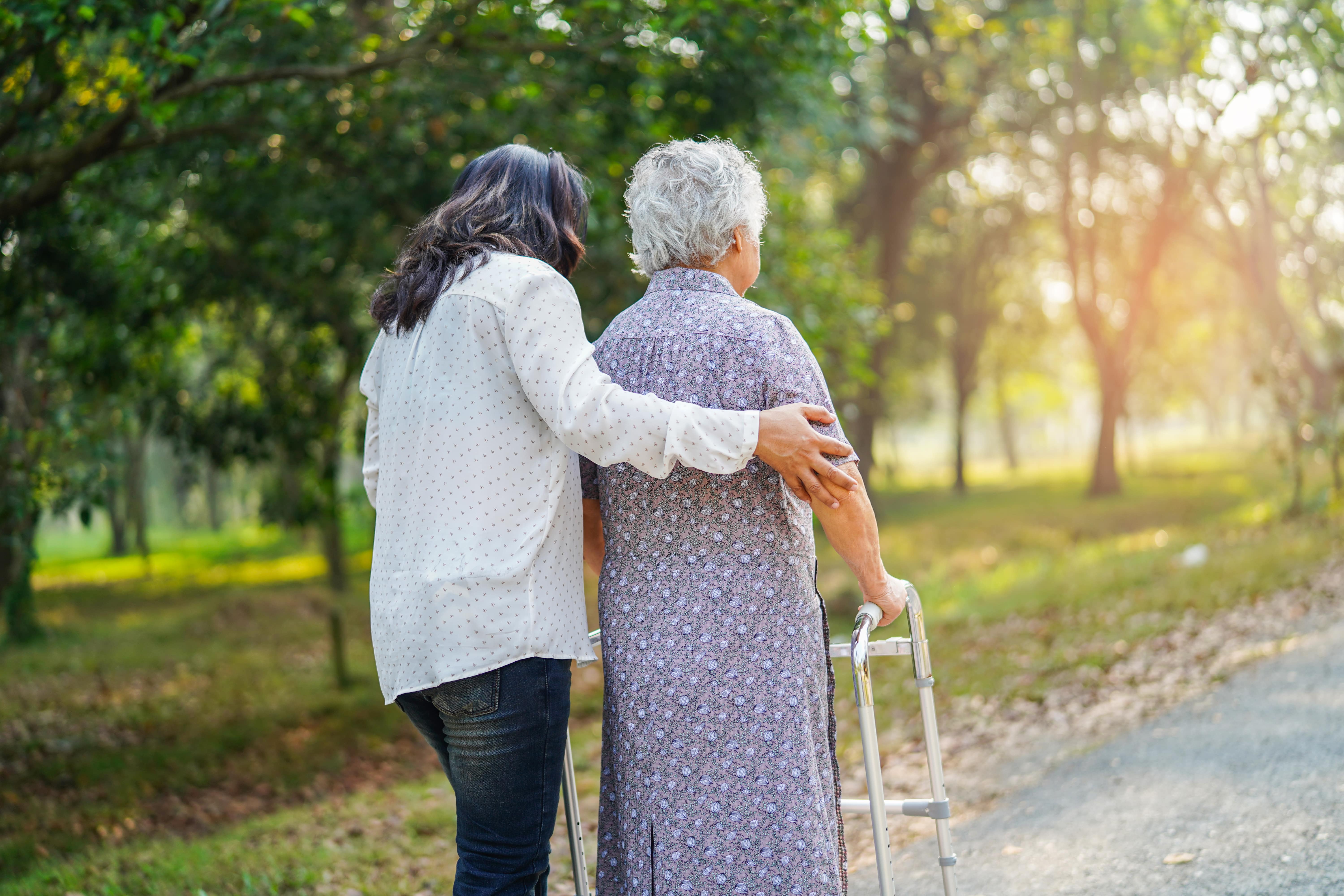 A caregiver supporting an older loved one using a walker